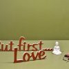 Medinis pastatomas užrašas "But first...Love"