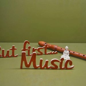Medinis pastatomas užrašas "But first...Music"