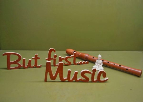 Medinis pastatomas užrašas "But first...Music"